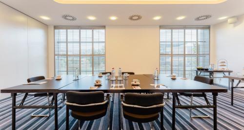 a conference room with tables and chairs and windows at PLAZA Premium Grand Winston in Rijswijk