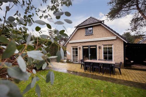 a house with a table and chairs in the yard at Welkom in ons huisje in het bos met prive sauna in Lunteren