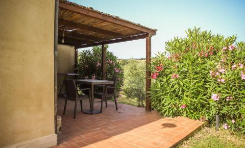 a patio with a table and chairs under a pergola at Bio Agriturismo Poggio Aione in Saturnia
