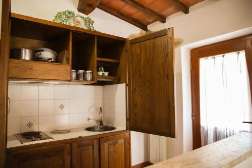 a kitchen with wooden cabinets and a sink at Bio Agriturismo Poggio Aione in Saturnia