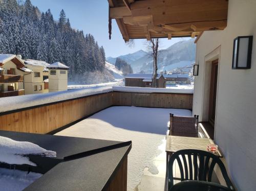 a balcony with a table and chairs and snow on the ground at Ferienwohnung Frauenkogelblick mit Terrasse in Grossarl