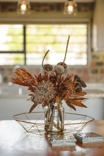 a glass vase with flowers in it on a table at Secure, luxurious with lovely views in Pringle Bay