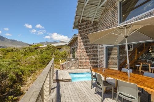 a patio with a wooden table and an umbrella at Secure, luxurious with lovely views in Pringle Bay