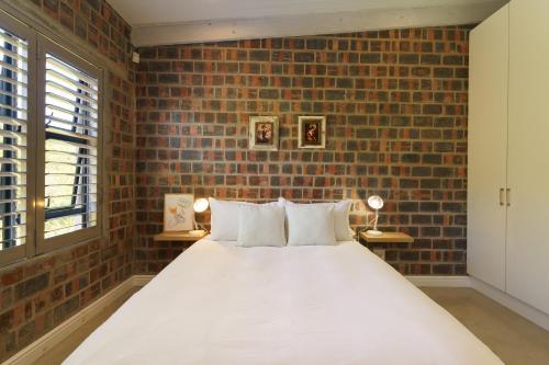 a bedroom with a bed with a brick wall at Secure, luxurious with lovely views in Pringle Bay