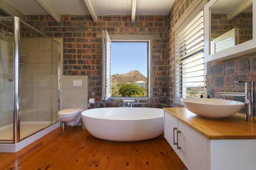 a bathroom with a large white tub and a window at Secure, luxurious with lovely views in Pringle Bay