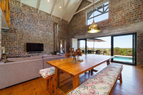 a living room with a wooden table and a couch at Secure, luxurious with lovely views in Pringle Bay
