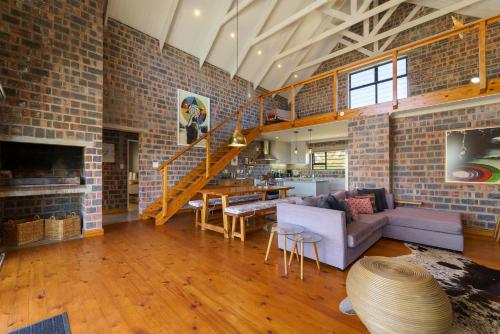 a living room with a staircase and a brick wall at Secure, luxurious with lovely views in Pringle Bay