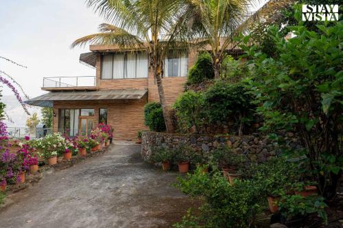 a house with palm trees and flowers in a driveway at StayVista at Laguna Escape with Deck, Pool, Bathtub in Wai