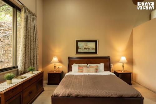 a bedroom with a bed and two lamps and a window at StayVista at Laguna Escape with Deck, Pool, Bathtub in Wai