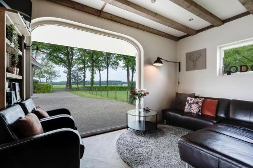 a living room with leather furniture and a large window at Boerenlodge 't Vennetje in Fluitenberg