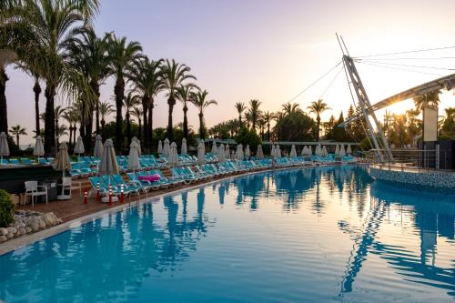 a large swimming pool with chairs and palm trees at AQI Pegasos World in Side