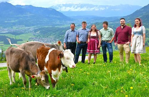 a group of people standing in a field with cows at Berghof Burtscher Niklas in Ludesch
