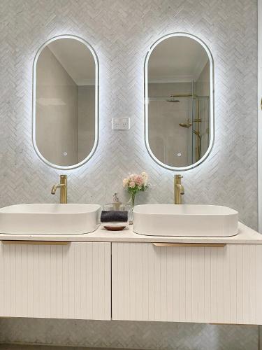 two sinks in a bathroom with two mirrors at Modern Family Oasis - 4BR, Free Parking, Steps to Shops & Train in Melbourne