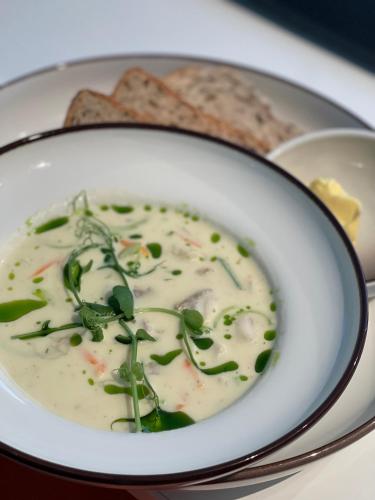 a bowl of soup on a plate with bread at Hemmingodden Lodge in Ballstad