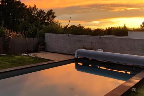 un coucher de soleil sur une piscine avec un banc dans l'établissement maison en Provence pour un été sous le soleil, à LʼIsle-sur-la-Sorgue