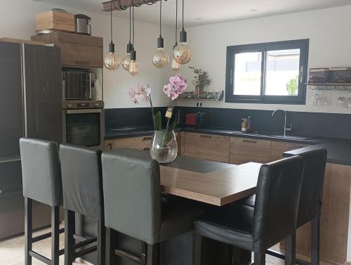 une cuisine avec une table, des chaises et un vase de fleurs dans l'établissement maison en Provence pour un été sous le soleil, à LʼIsle-sur-la-Sorgue