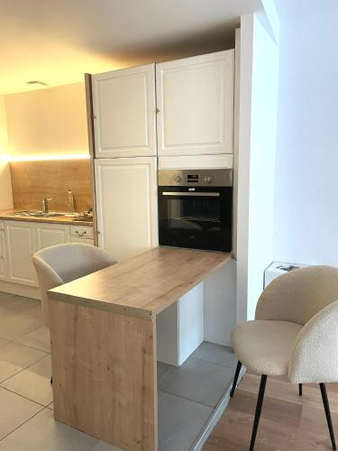une cuisine avec des placards blancs et un comptoir en bois avec des chaises dans l'établissement Loft spa, cour arrière privée, à Labruguière