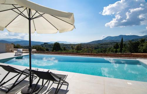 a pool with two chairs and an umbrella at Pentacle Villas in Lefkada Town