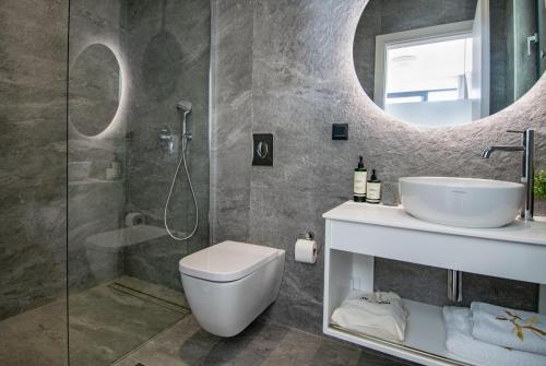 a bathroom with a toilet and a sink and a mirror at Pentacle Villas in Lefkada Town