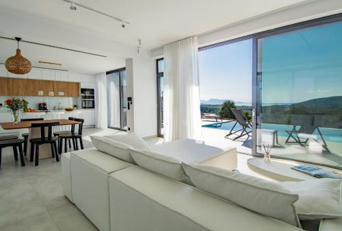 a living room with white furniture and a large window at Pentacle Villas in Lefkada Town