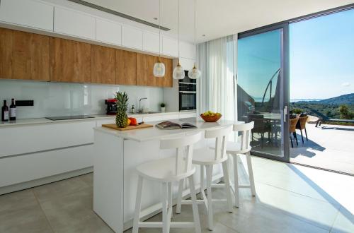a kitchen with white cabinets and a counter with stools at Pentacle Villas in Lefkada Town