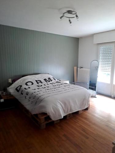 a bedroom with a bed with a white comforter at 140 m2 , 3 lits 2 place et 1 canapé convertible 2 place in Lanvaudan