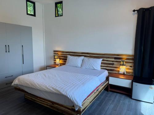 Un dormitorio con una cama grande y dos mesitas de noche. en Real Hostel, en Kaôh Rŭng (3)