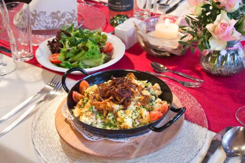 a table with a pan of food and a plate of salad at Alpengasthof Gern Alm in Pertisau