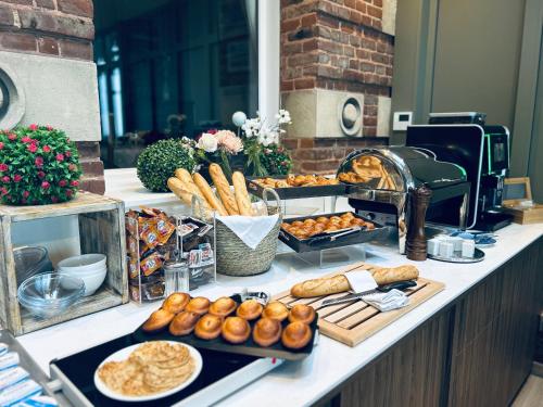 un buffet avec du pain et des viennoiseries sur un comptoir dans l'établissement Logis Hôtel- Restaurant Le Relais Guillaume de Normandy, à Saint-Valery-sur-Somme
