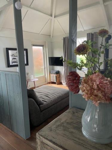a living room with a couch and a vase of flowers at Holiday cottage de Garage Inn in Hank