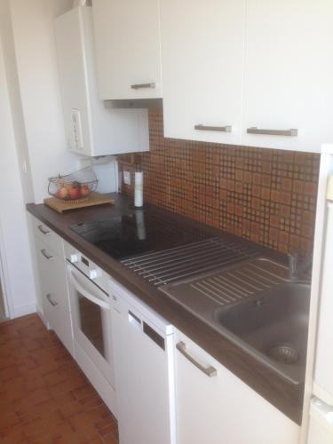 une cuisine avec des armoires blanches et un comptoir noir dans l'établissement T2 dans résidence de standing, à Royan