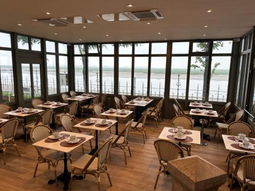 un restaurant avec des tables, des chaises et des fenêtres dans l'établissement Logis Hôtel- Restaurant Le Relais Guillaume de Normandy, à Saint-Valery-sur-Somme