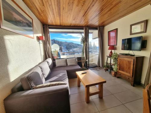 a living room with a couch and a tv at Logement entier, plein sud, pied des pistes, Chamrousse 1650 in Chamrousse