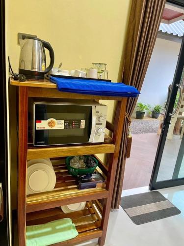 a microwave sitting on top of a wooden shelf at Baan rabianglay 2 in Ban Hin Sam Kon