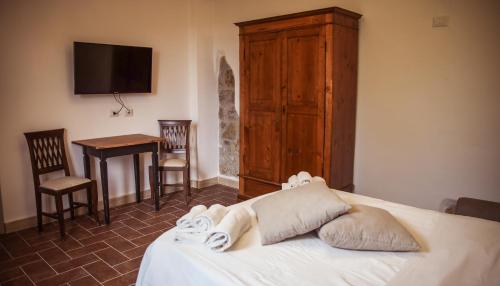 a bedroom with a bed and a table and a television at Bio Agriturismo Poggio Aione in Saturnia