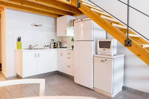 une cuisine avec des armoires blanches et un réfrigérateur blanc dans l'établissement Le Petit Turbil, à Lyon