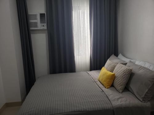 a bedroom with a bed with two pillows and a window at 642 - Quiet & secured condo in Cavite with HI speed WIFI in Dasmariñas