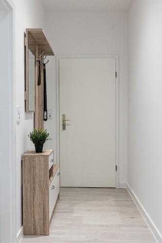 a hallway with a white door and a potted plant at Nordic Comfort Apartments in Bremerhaven