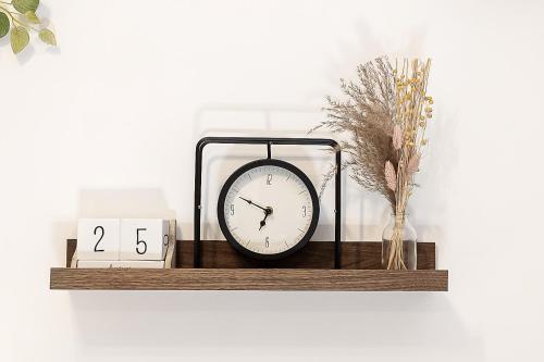 a clock sitting on a wooden shelf with a clock at Nordic Comfort Apartments in Bremerhaven