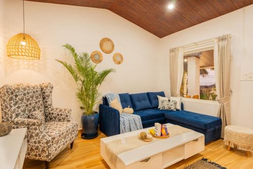 a living room with a blue couch and chairs at ELIVAAS House of Neptune 1 BHK Boutique Villa on the Beach in Morjim