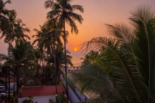 a sunset view from the balcony of a resort with palm trees at ELIVAAS House of Neptune 1 BHK Boutique Villa on the Beach in Morjim