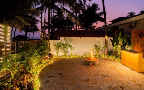 a fire pit in a courtyard with palm trees at ELIVAAS House of Neptune 1 BHK Boutique Villa on the Beach in Morjim