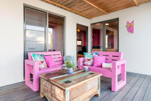a porch with two pink chairs and a coffee table at SOBIESZEPTY Odetchnij ciszą in Gdańsk