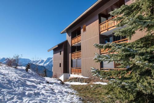 un bâtiment situé sur le côté d'une montagne enneigée dans l'établissement Appartement cosy à L'Alpe d'Huez 27 m² avec vue montagne, à L'Alpe-d'Huez