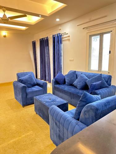 a large living room with blue couches and chairs at Luxury Villa in Heart of the city in Haidar Sāhibgūda