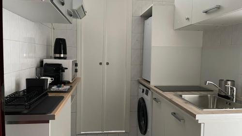une cuisine blanche avec un évier et un plan de travail dans l'établissement Studio aux portes de Paris, à Ivry-sur-Seine