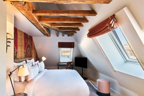 a bedroom with a white bed and some windows at Maison Barrière Vendôme in Paris