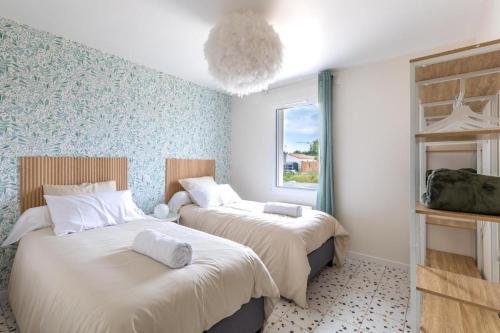 deux lits dans une chambre aux murs bleus dans l'établissement Les Lauriers de Catherine, à Saint-Jean-de-Monts