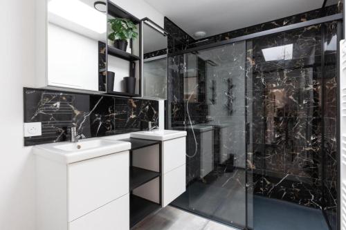 La salle de bains est pourvue d'un lavabo et d'une douche avec du carrelage noir. dans l'établissement Les Lauriers de Catherine, à Saint-Jean-de-Monts