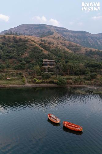 two boats in a body of water with mountains in the background at StayVista at Laguna Escape with Deck, Pool, Bathtub in Wai